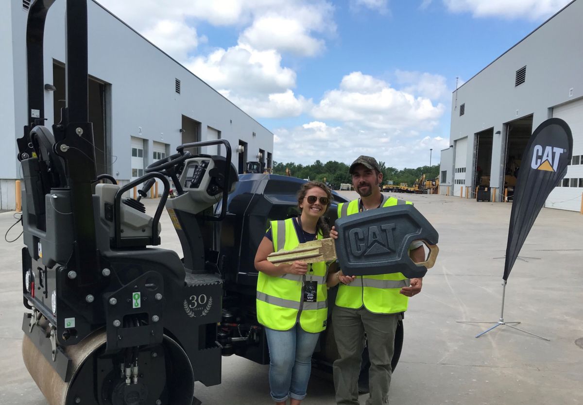 Jaimee and Andrew Mallett holding the “key” to their new Cat CB24B small tandem vibratory roller.