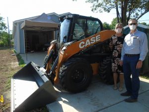 Ann Fox with Habitat and Troy Williams with CASE and the donated skid steer