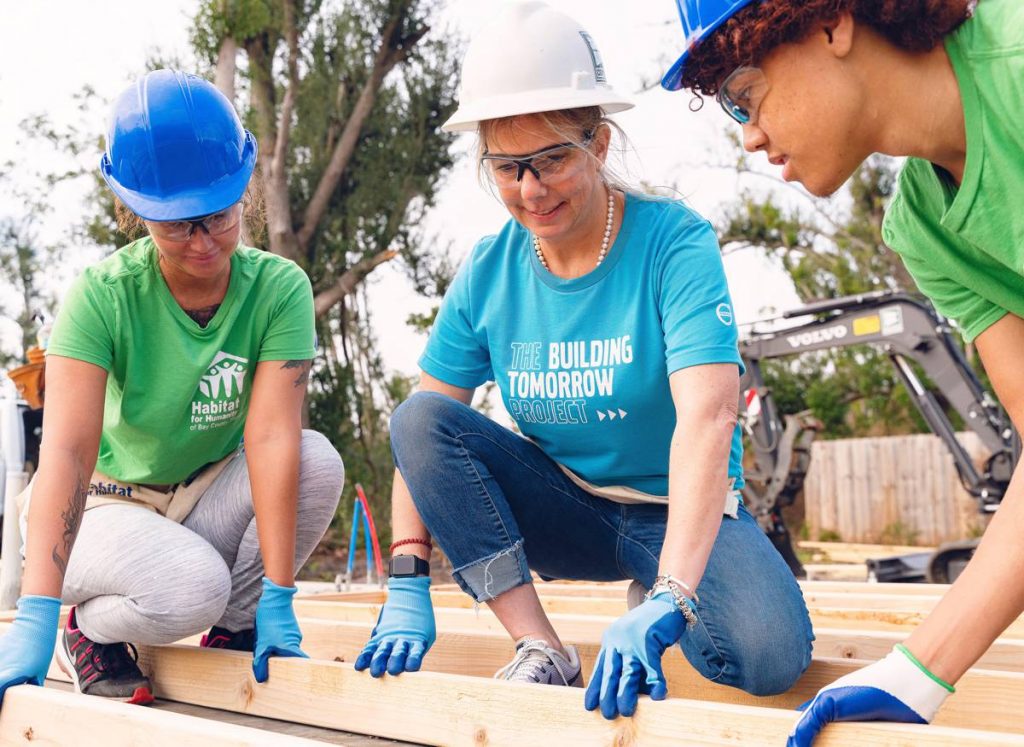 A volunteer from Volvo CE (in blue) works alongside the future homeowner and her son in February 2020