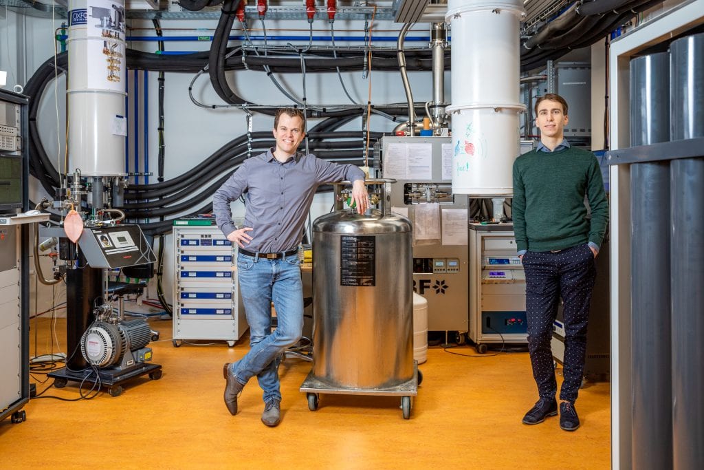 Menno Veldhorst and Nico Hendrickx standing next to the setup hosting the germanium quantum processor.