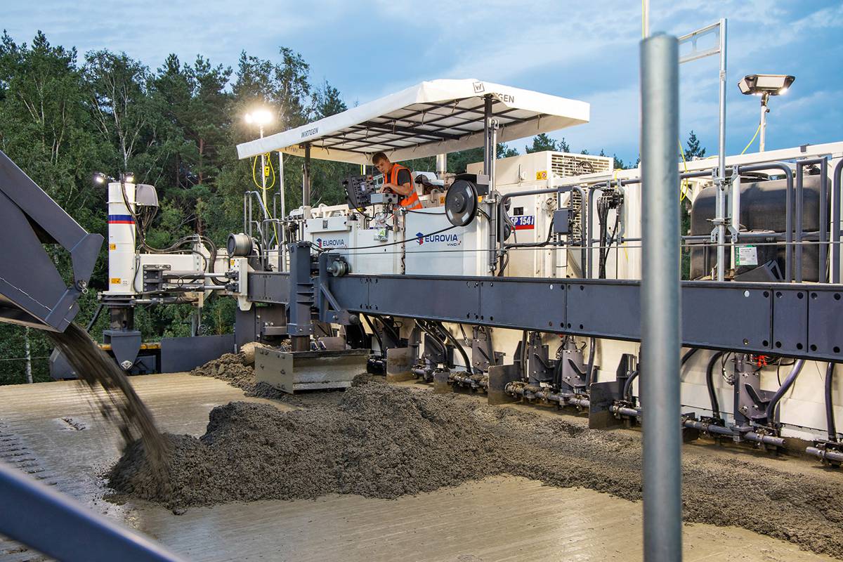 A belt conveyor is used to convey the top layer concrete over and across the first SP 154(i) (operating as a bottom layer paver) onto the freshly paved bottom layer concrete directly in front of the second SP 154(i) (operating as a top layer paver) for further processing.