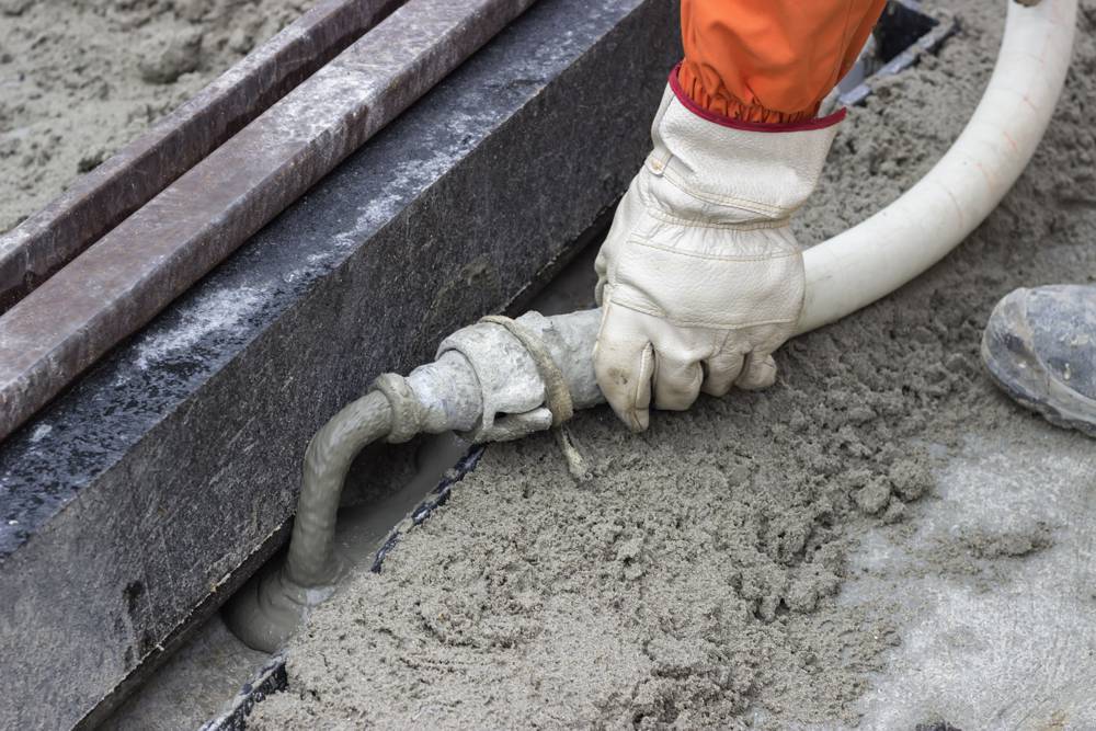 Mortar from grout mixer and delivery system, grouting pump used to settle the grout into the joints. Grouting mortar and tram track laying. Selective focus and shallow dof.