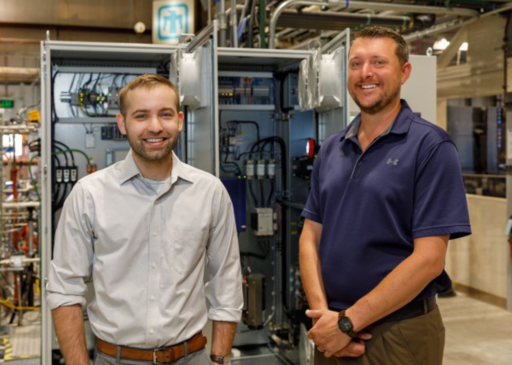 Credit: Photo by Bret Latter/Sandia National Laboratories Logan Rapp (left) and Darryn Fleming, Sandia National Laboratories mechanical engineers, stand with the control system for the supercritical carbon dioxide Brayton cycle test loop. Earlier this year, the engineers delivered electricity produced by this system to the grid for the first time.