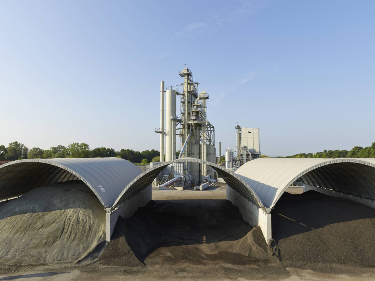 Roofs for dry storage of virgin mineral and recycling material save a large amount of fuel and therefore CO₂ during drying and heating of the material.