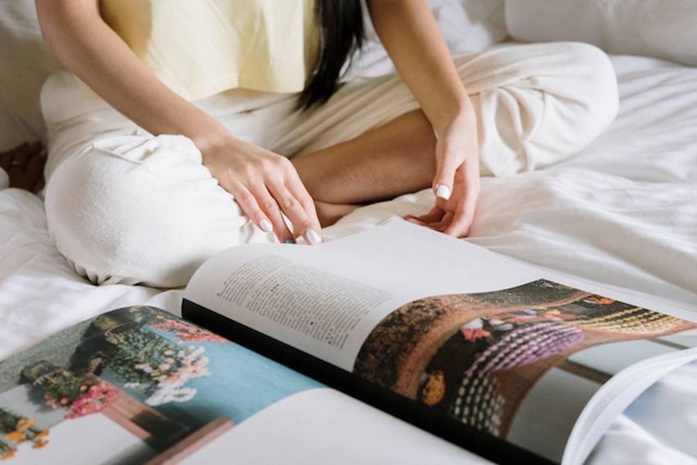 Person reading a magazine while sitting on a bed