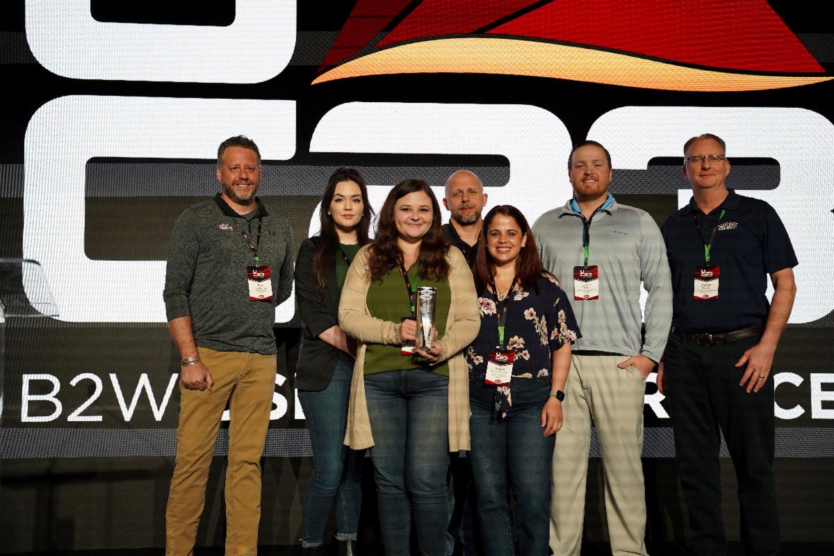 Jessica Paske (holding award) and the Superior Construction Company team accept the 2023 Best ROI with the B2W Platform award for the company’s success with the unified B2W Platform.