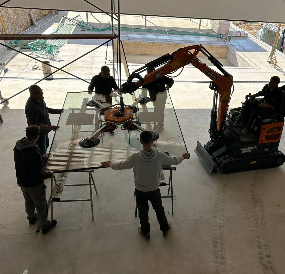 Using a Develon Mini-Excavator to install Large Glass Panels