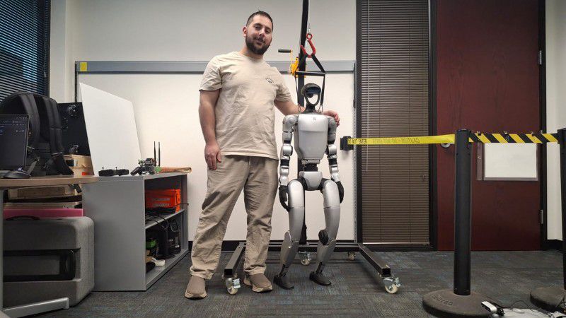 Credit: Photo courtesy of Eren Sadıkoğlu/ASU Eren Sadıkoğlu, who is currently pursuing his master’s degree in robotics and autonomous systems, poses with a humanoid robot in the LENS Lab. Sadıkoğlu is working on AI solutions that will allow the Unitree Go2 robotic dog to undertake search-and-rescue missions in dangerous environments, such as in the aftermath of earthquakes.